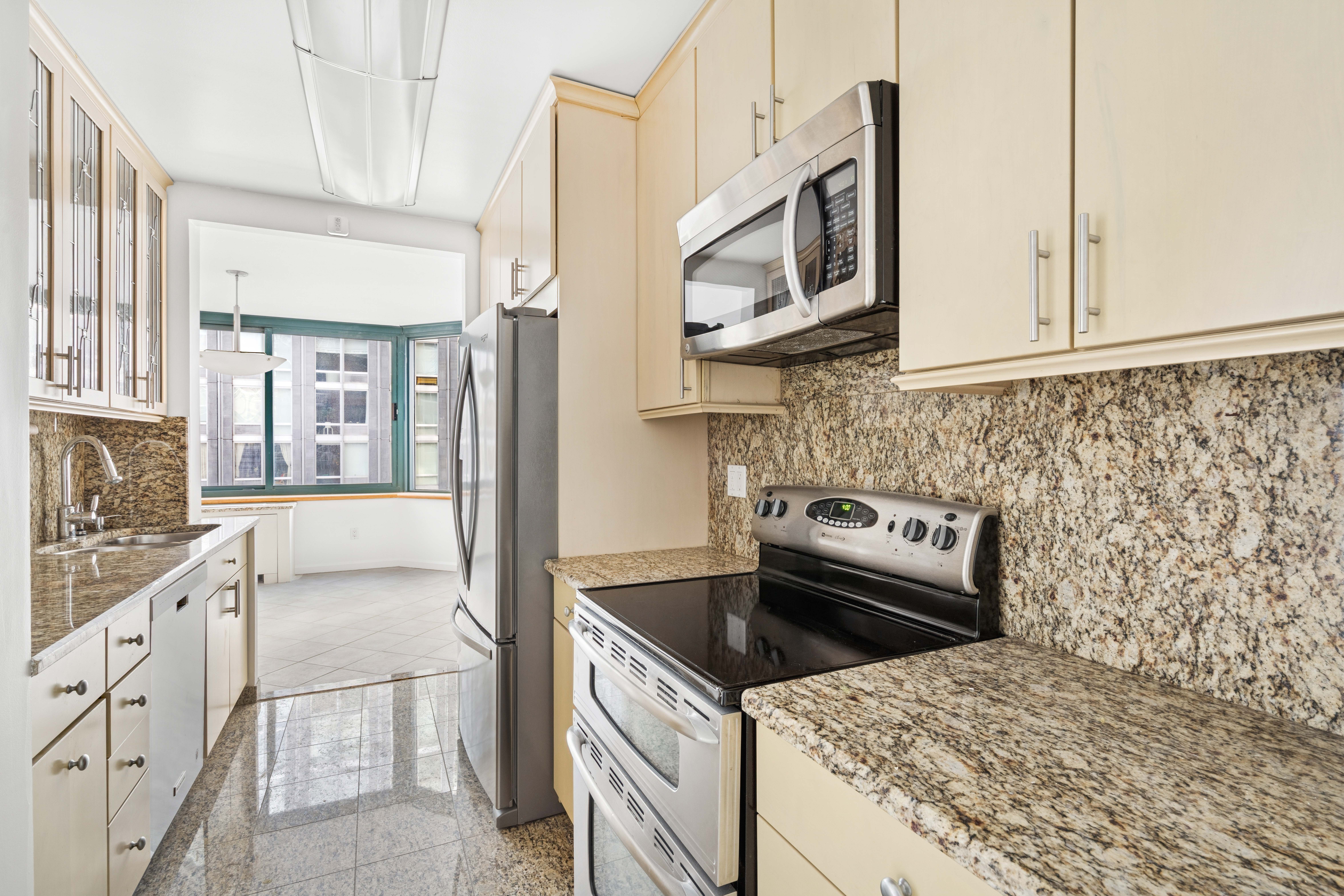 201 West 72nd Street, Unit 8A Manhattan, NY 10023 - Photo 5 of 15 a kitchen with stainless steel appliances granite countertop a sink stove and microwave