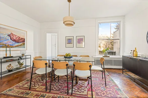 a dining room with wooden floor a chandelier a wooden table and chairs