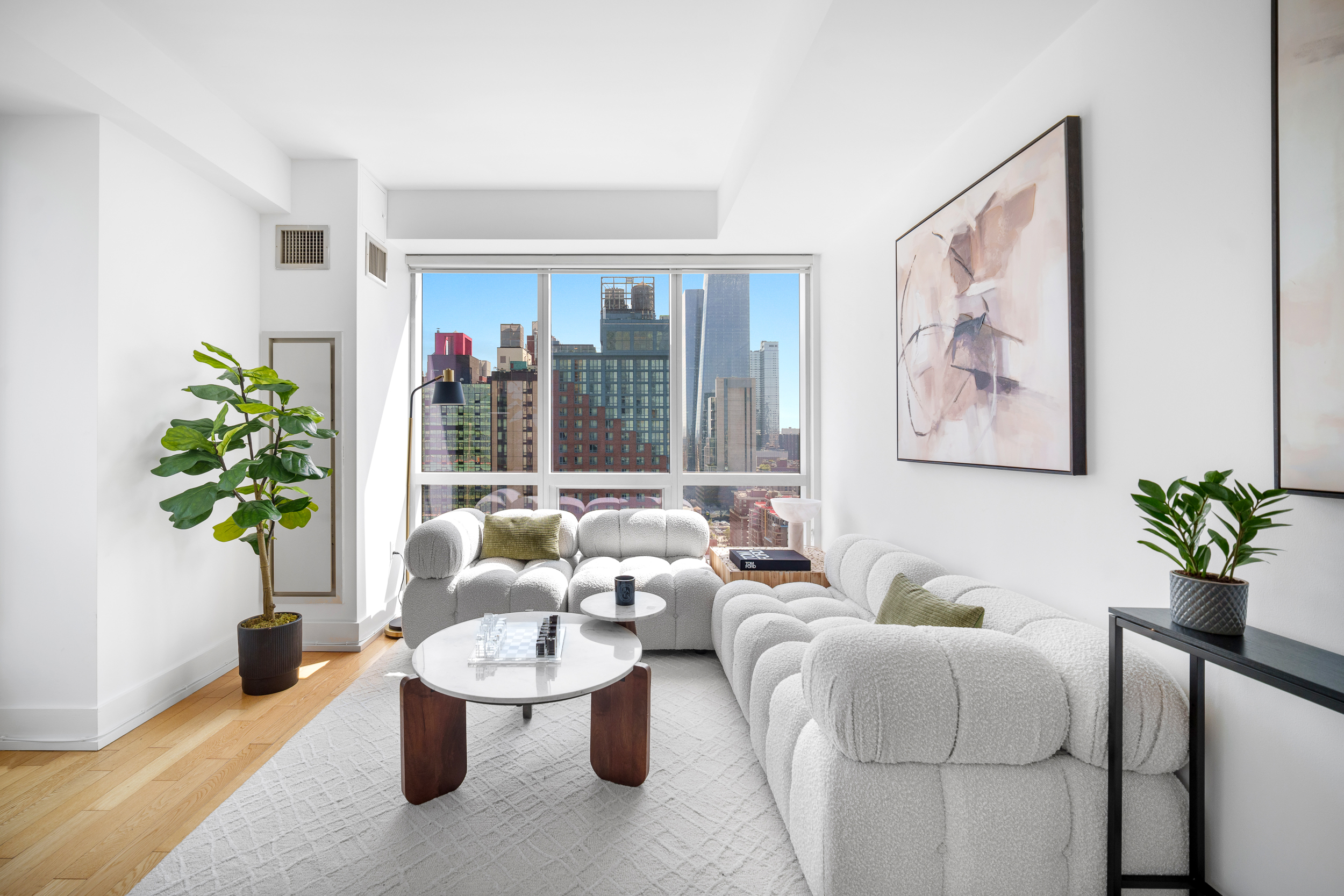 350 West 42nd Street, Unit 27K Manhattan, NY 10036 - Photo 2 of 18 a living room with furniture and a potted plant