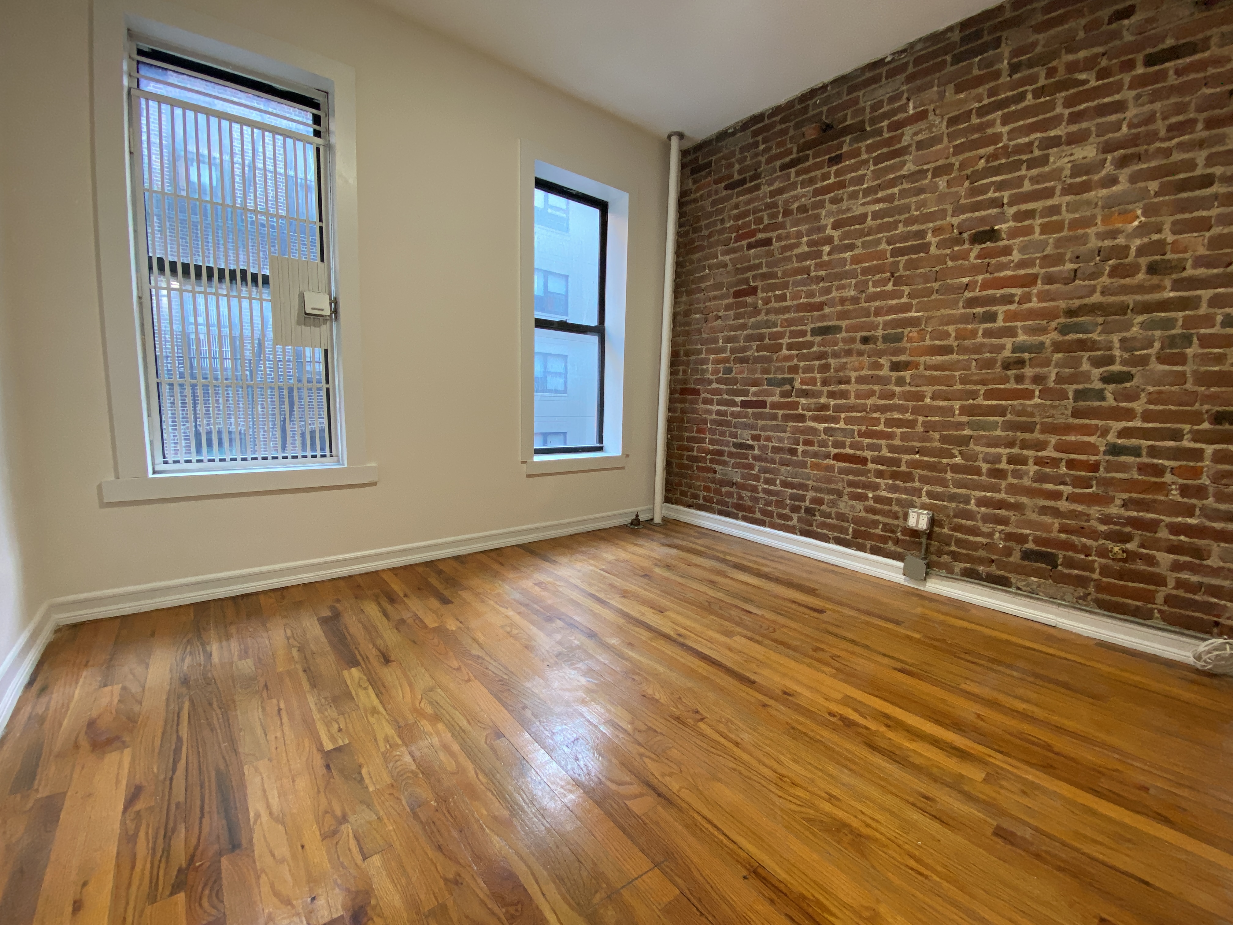 435 East 75th Street, Unit 10 Manhattan, NY 10021 - Photo 3 of 6 a view of an empty room with wooden floor and a window