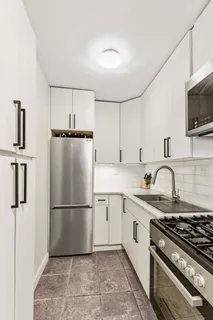 a kitchen with granite countertop a refrigerator stove top oven and sink