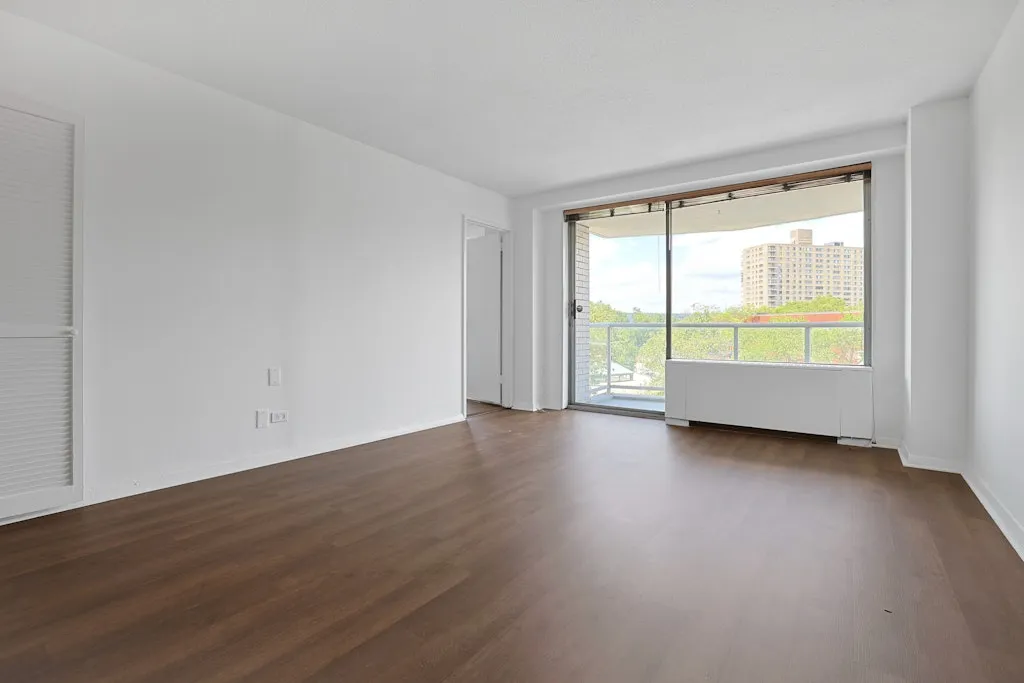 a view of an empty room with wooden floor and a window