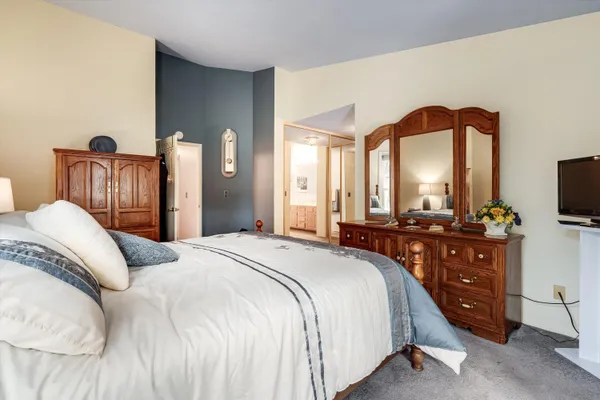 a bedroom with bed and a flat tv screen on dresser