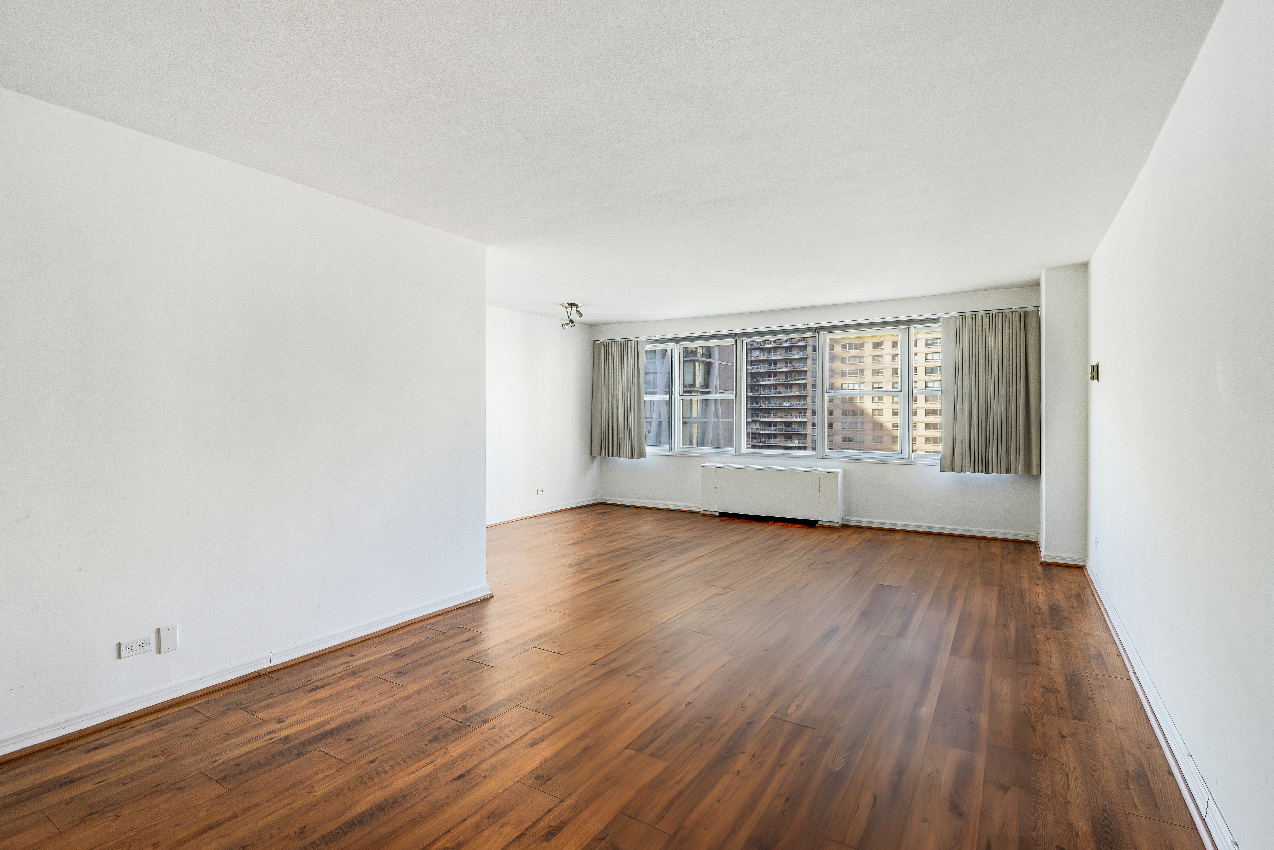 155 West 68th Street, Unit 1907 Manhattan, NY 10023 - Photo 2 of 20 an empty room with wooden floor and windows
