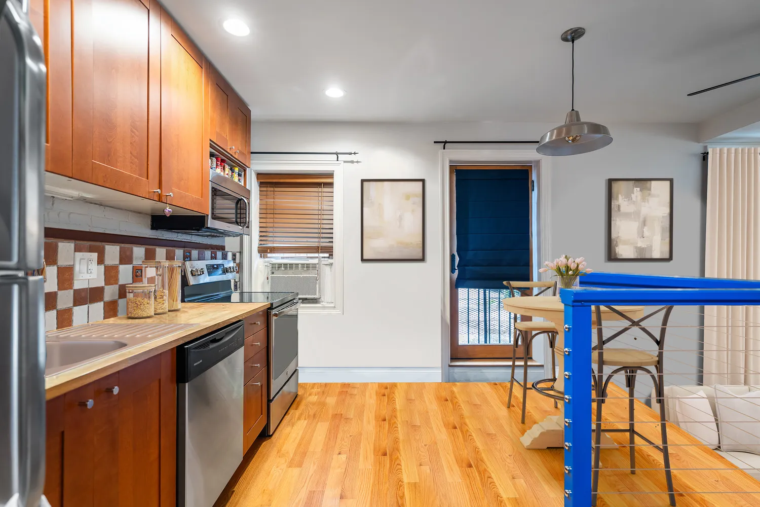 a kitchen with stainless steel appliances granite countertop a refrigerator a sink dishwasher a stove and a dining table with wooden floor