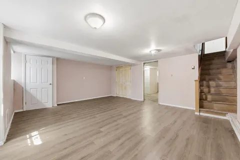 a view of an empty room with wooden floor and closet