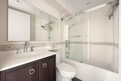 a bathroom with a sink vanity granite toilet and shower