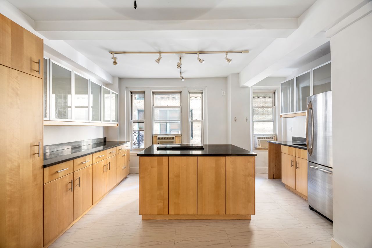 325 West 45th Street, Unit 205 Manhattan, NY 10036 - Photo 2 of 14 a large kitchen with stainless steel appliances granite countertop a refrigerator a sink dishwasher a stove and white countertops with wooden floor