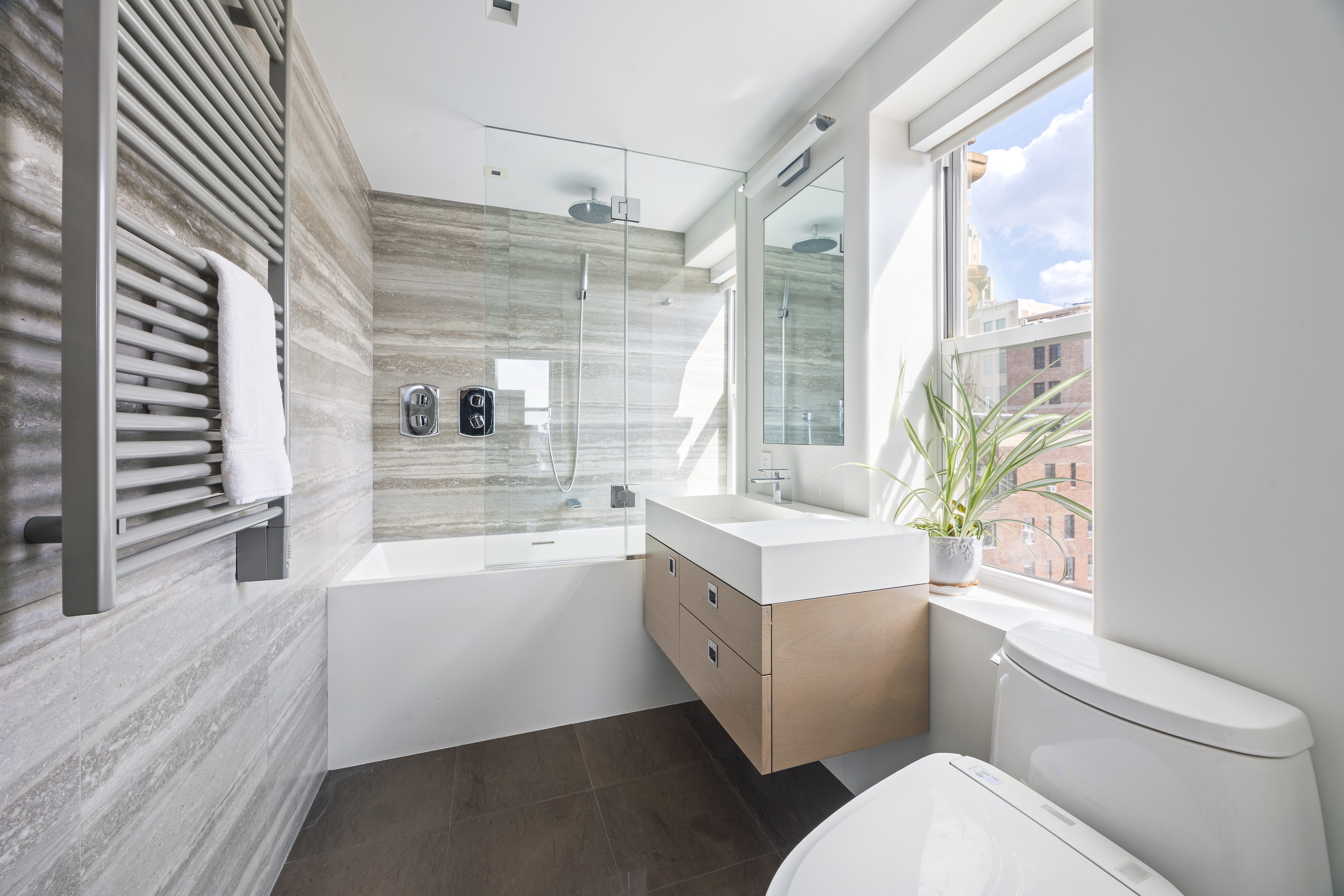 24 5th Avenue, Unit PH1701 Manhattan, NY 10011 - Photo 20 of 24 a bathroom with a sink a toilet a mirror and a bathtub