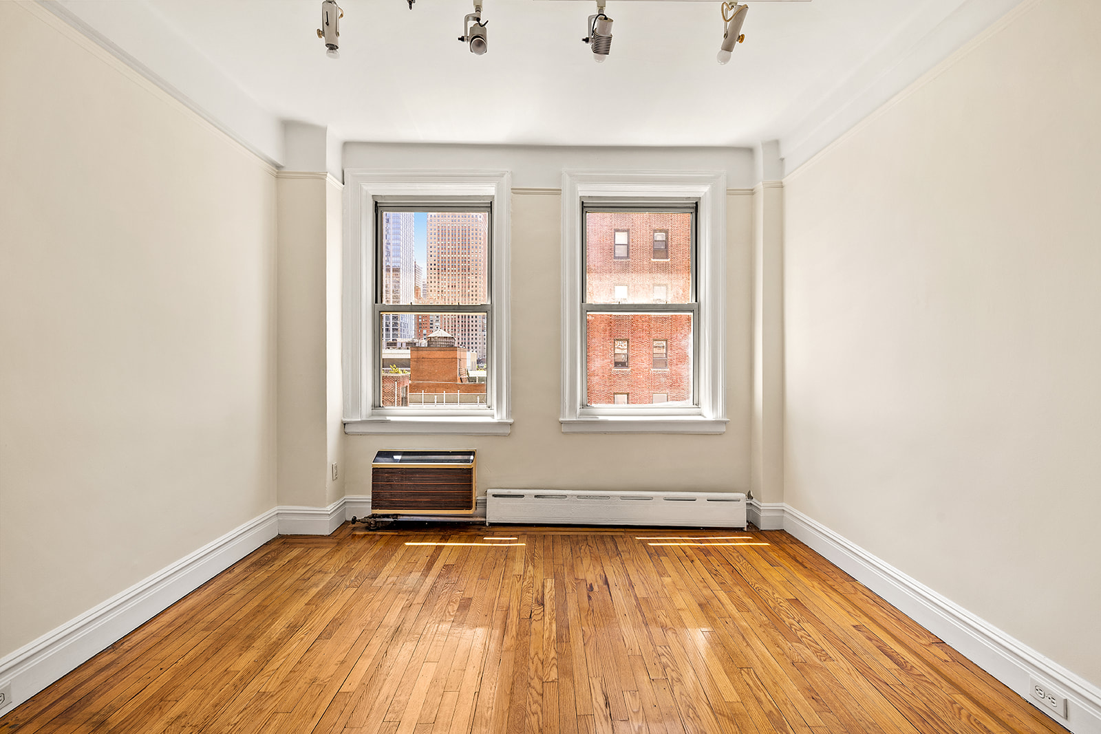 345 West 55th Street, Unit 8AB Manhattan, NY 10019 - Photo 10 of 14 an empty room with wooden floor and windows
