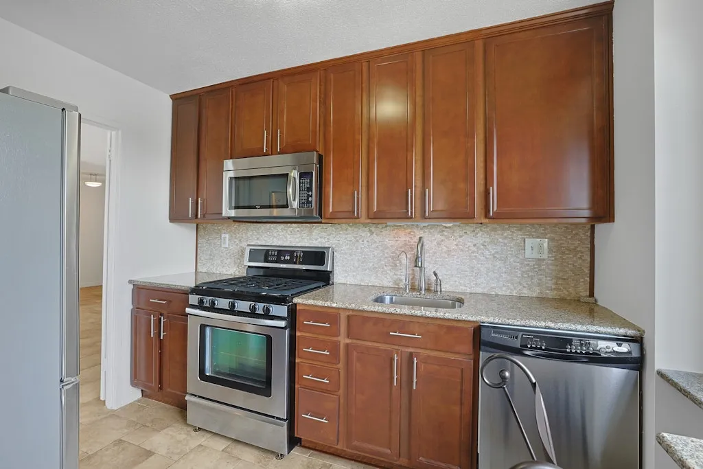 a kitchen with granite countertop wooden cabinets and stainless steel appliances