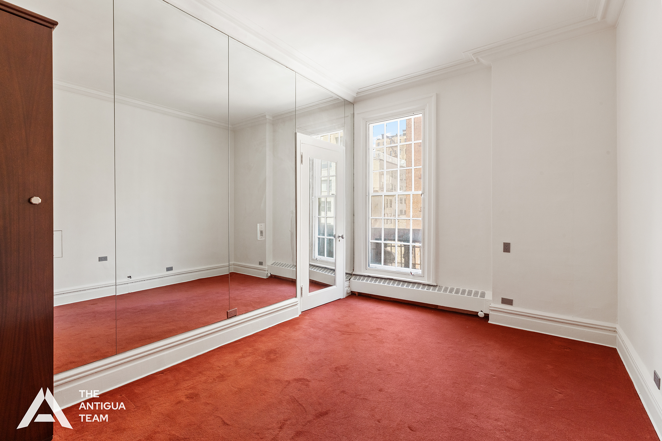 45 East 66th Street, Unit 4W Manhattan, NY 10065 - Photo 14 of 27 an empty room with wooden floor and windows with curtains