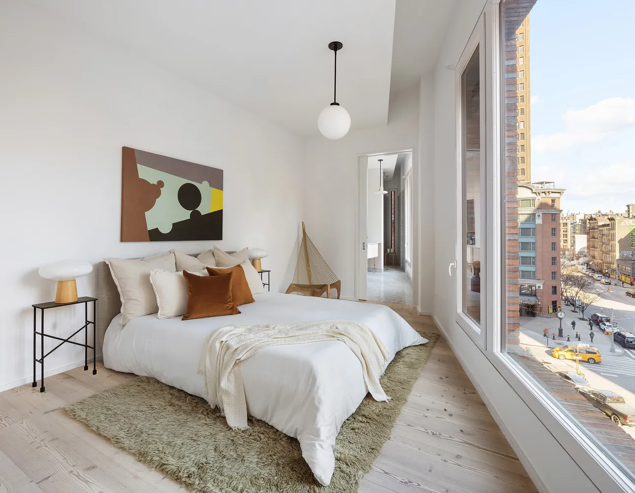 a bedroom with bed and a large mirror next to a window
