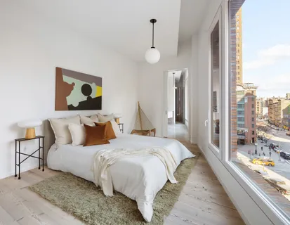 a bedroom with bed and a large mirror next to a window