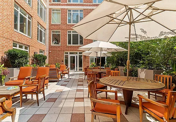205 East 85th Street, Unit G10 Manhattan, NY 10028 - Photo 20 of 27 a view of a patio with a dining table and chairs under an umbrella with barbeque grill and a fire pit
