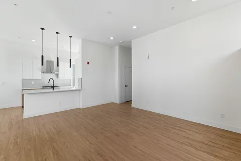 a view of an empty room with wooden floor and stairs