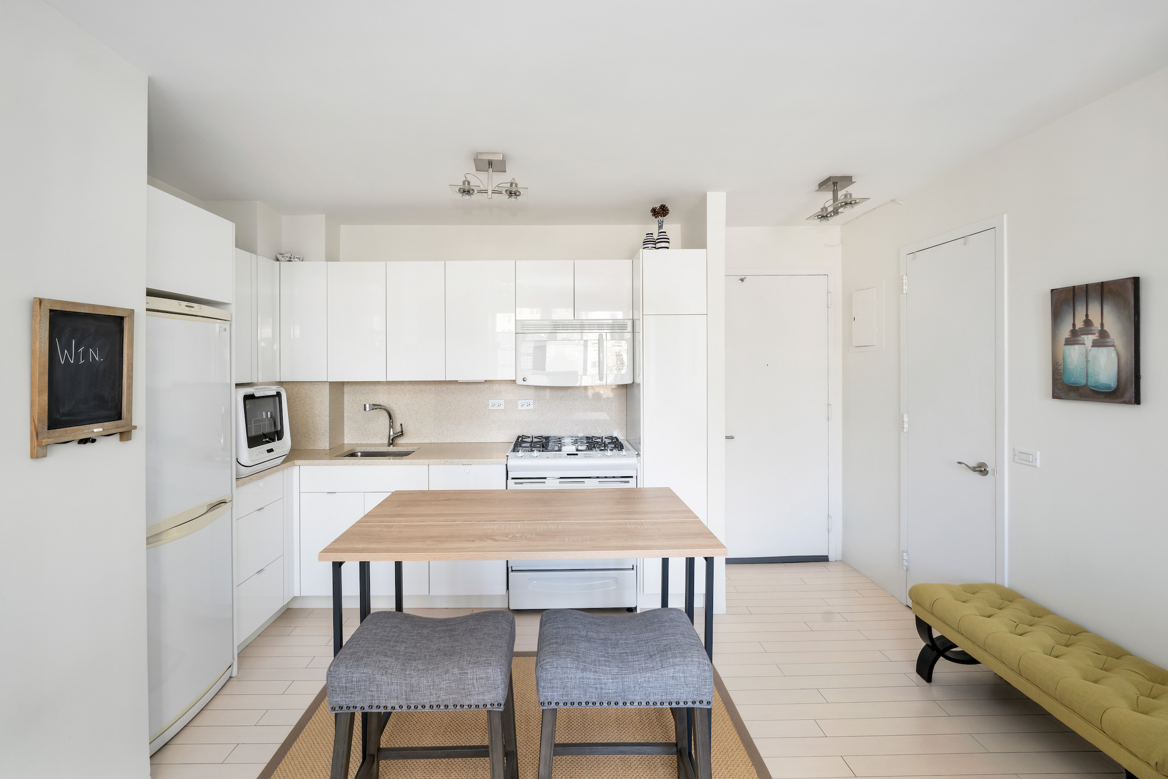 2373 Broadway, Unit 1425 Manhattan, NY 10024 - Photo 5 of 13 a kitchen with a table chairs refrigerator and cabinets