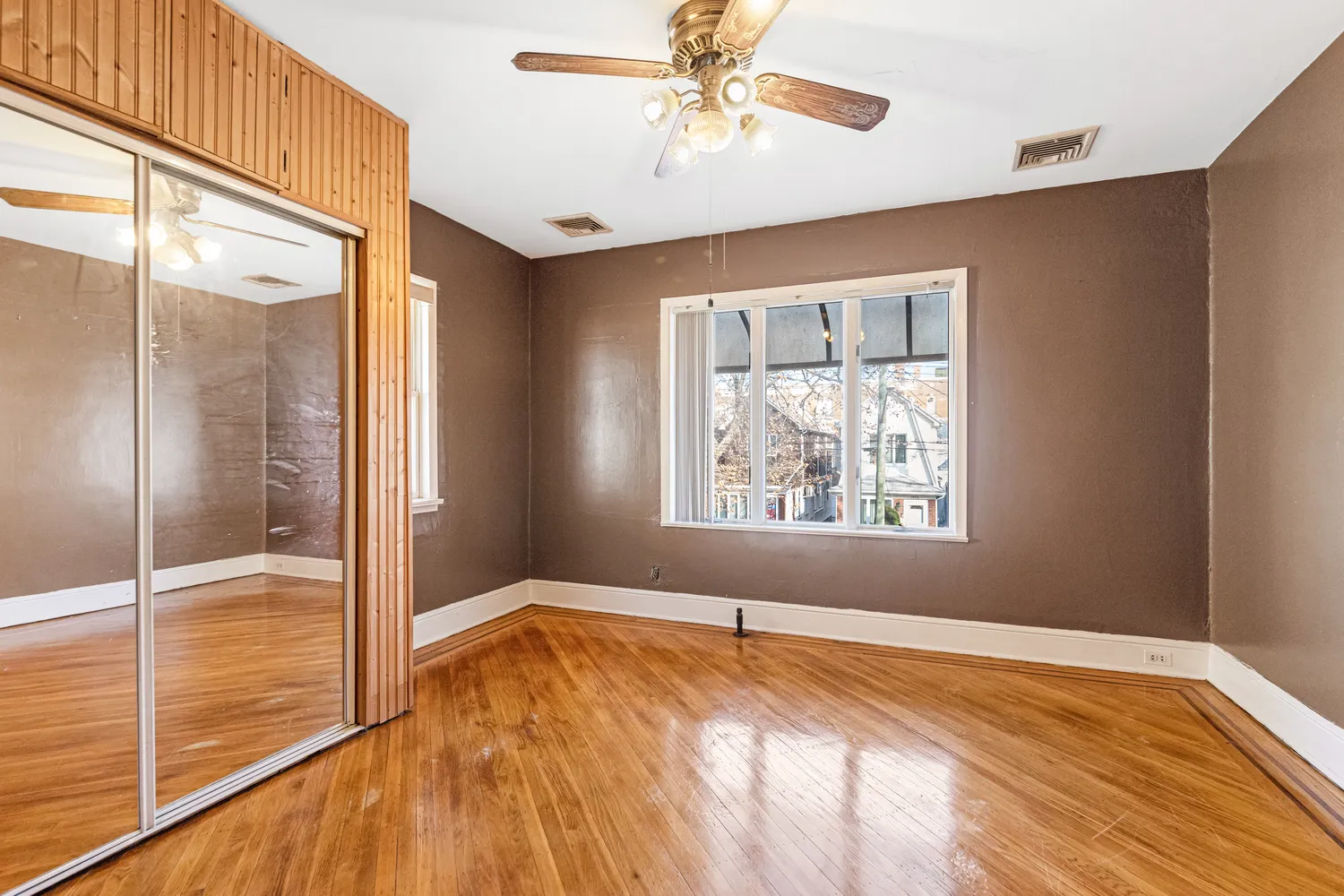 a view of empty room with wooden floor and fan