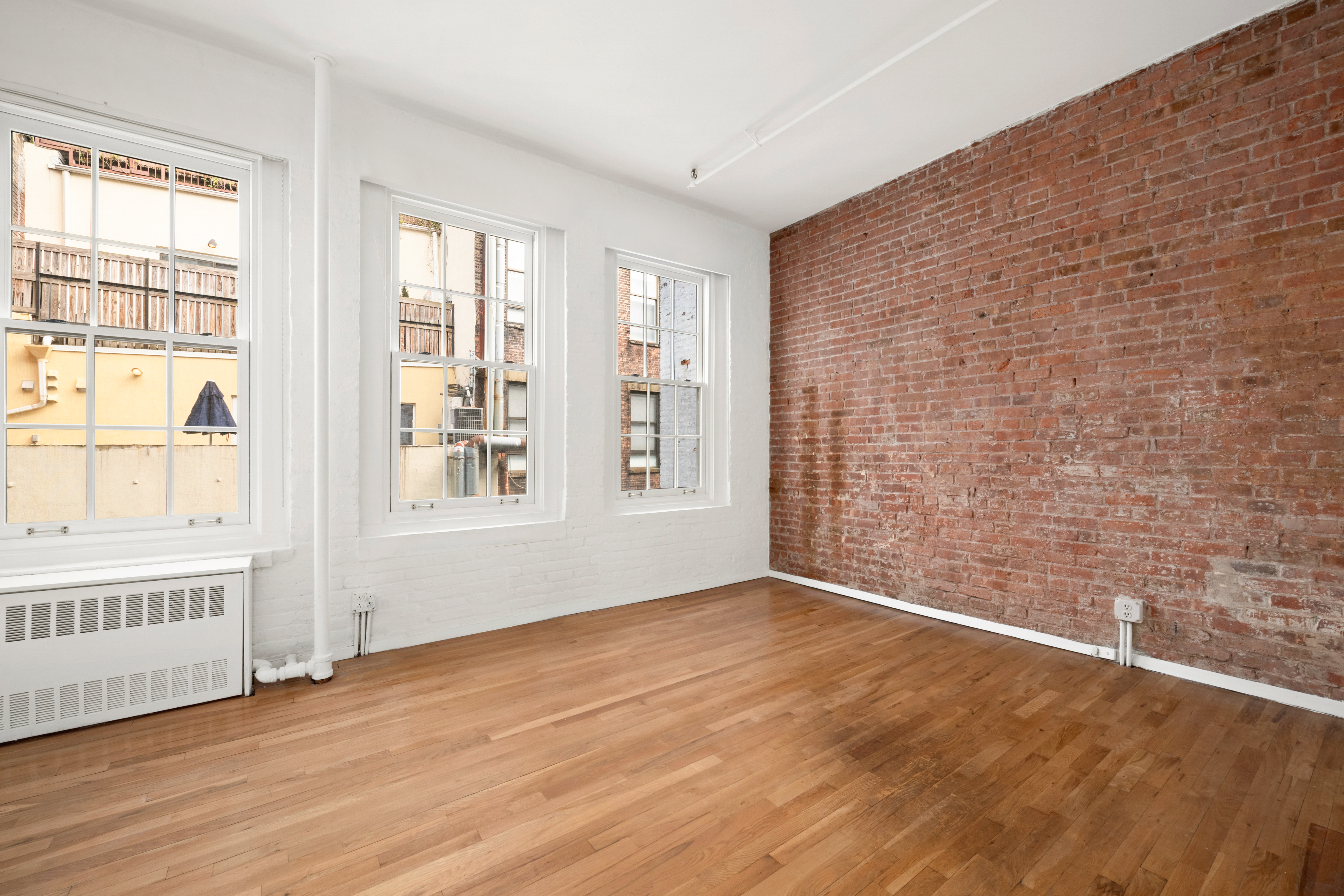 140 Thompson, Unit 4A Manhattan, NY 10012 - Photo 5 of 13 a view of an empty room with a window and wooden floor