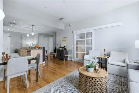 a living room with furniture and a dining table with wooden floor