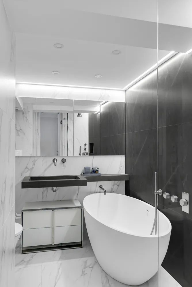 a bathroom with a white bath tub a mirror and a sink