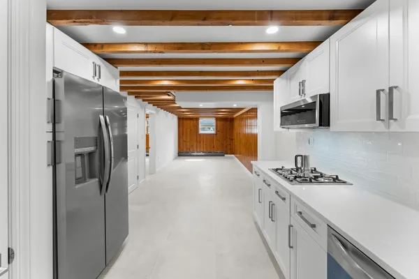 a kitchen with stainless steel appliances granite countertop a refrigerator a sink and white cabinets