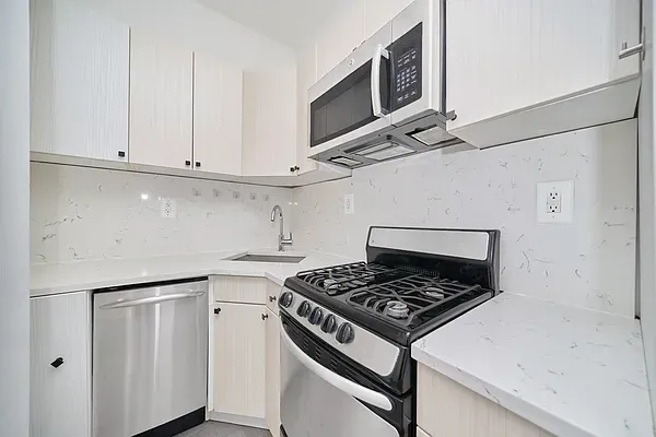 a kitchen with white cabinets and appliances