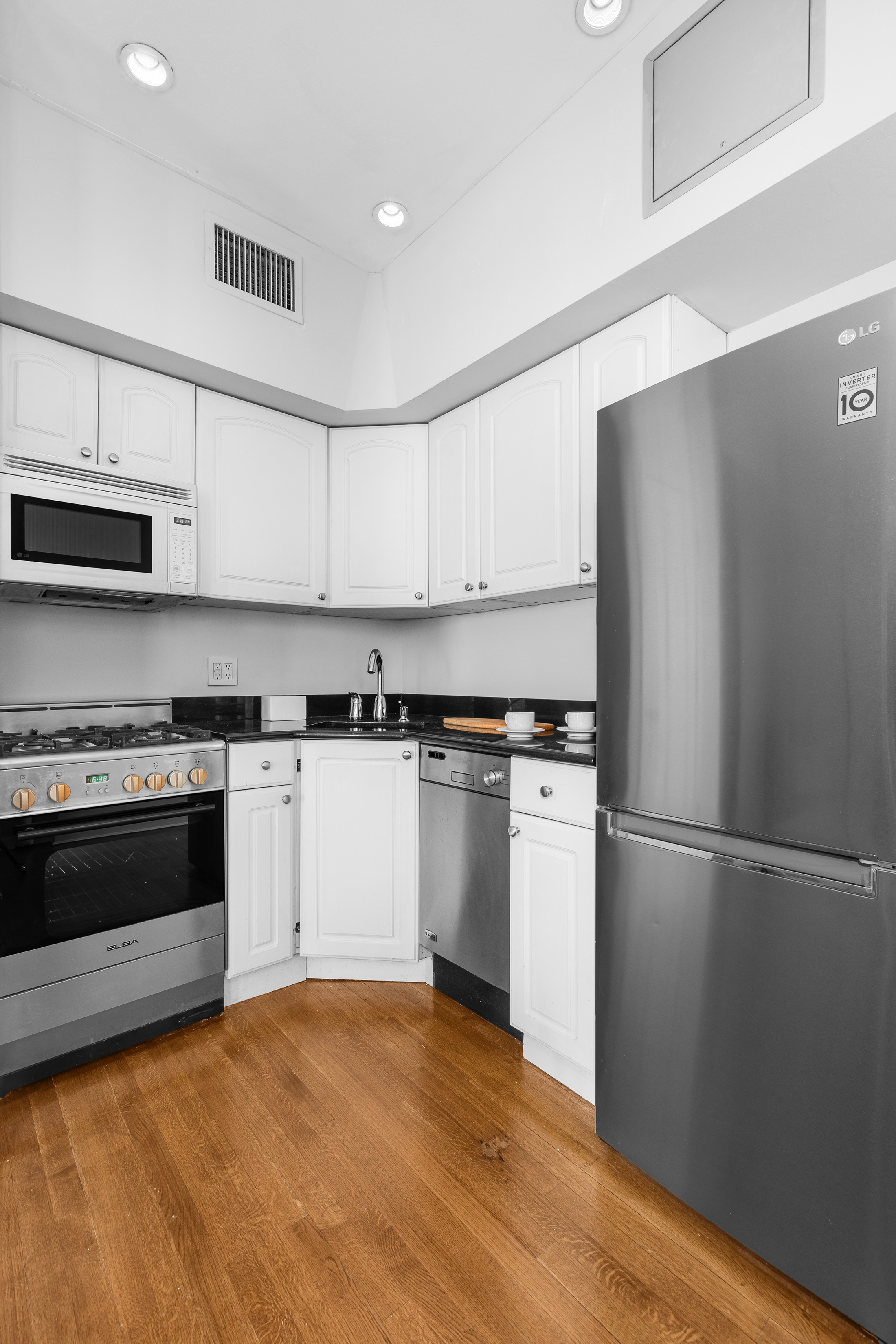 92 Perry Street, Unit 6 Manhattan, NY 10014 - Photo 6 of 10 a kitchen with a refrigerator stove and white cabinets