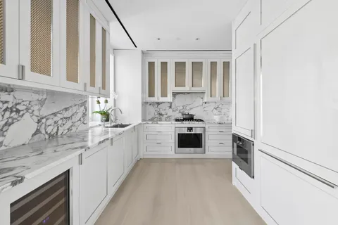 a kitchen with stainless steel appliances kitchen island granite countertop white cabinets and window
