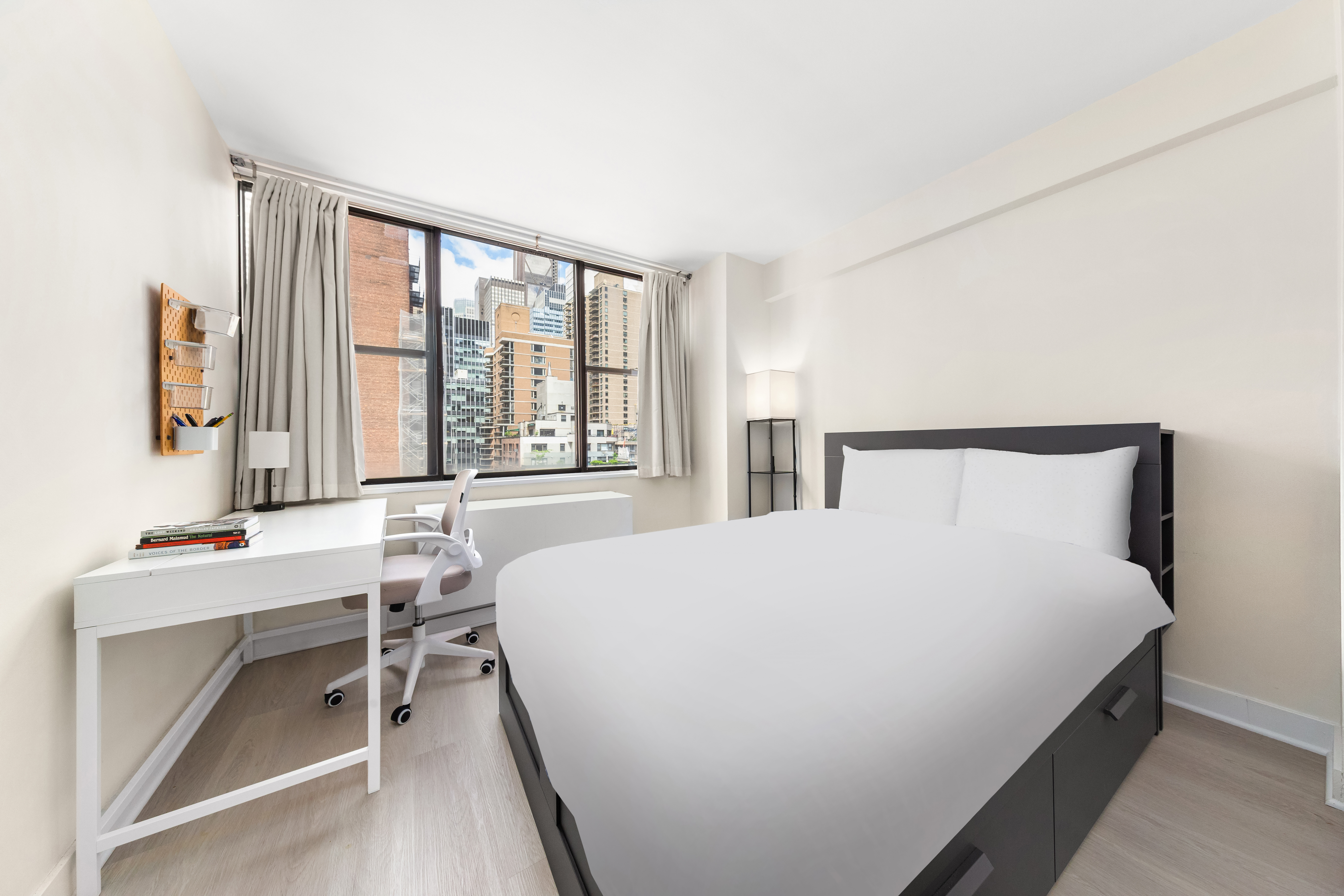 301 East 45th Street, Unit 11F Manhattan, NY 10017 - Photo 4 of 9 a bedroom with a bed table chair and a window