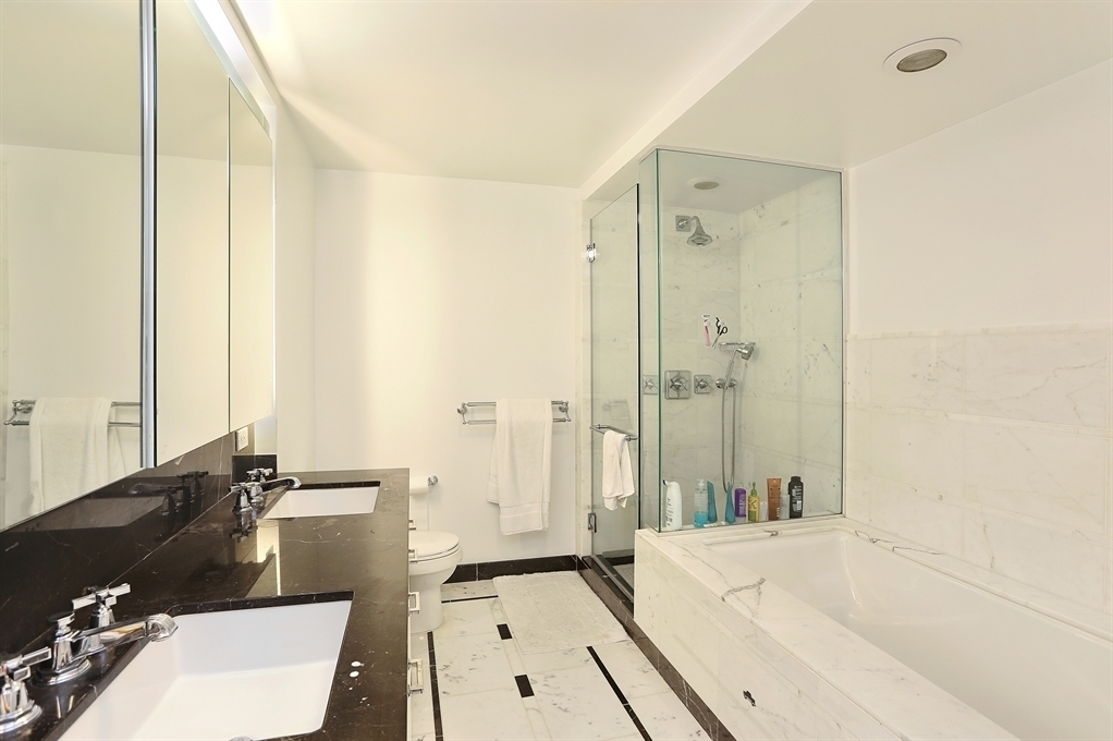 205 East 85th Street, Unit 10E Manhattan, NY 10028 - Photo 6 of 7 a bathroom with a tub sink and mirror