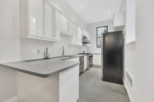 a kitchen with stainless steel appliances granite countertop a refrigerator a sink a stove and white cabinets