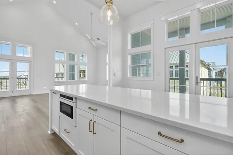 an empty room with wooden floor cabinet and windows
