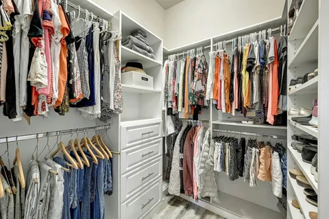 a view of walk in closet with clothes and shoes