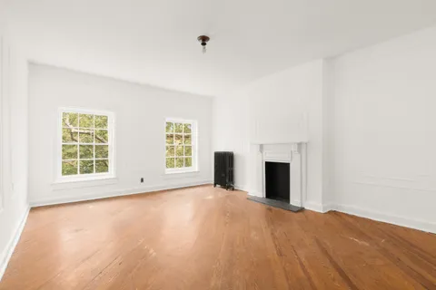 an empty room with windows and fireplace