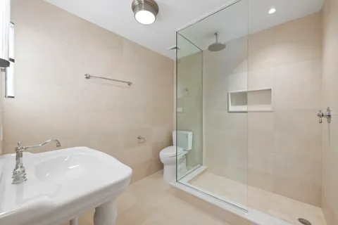 a spacious bathroom with a double vanity sink toilet mirror and shower