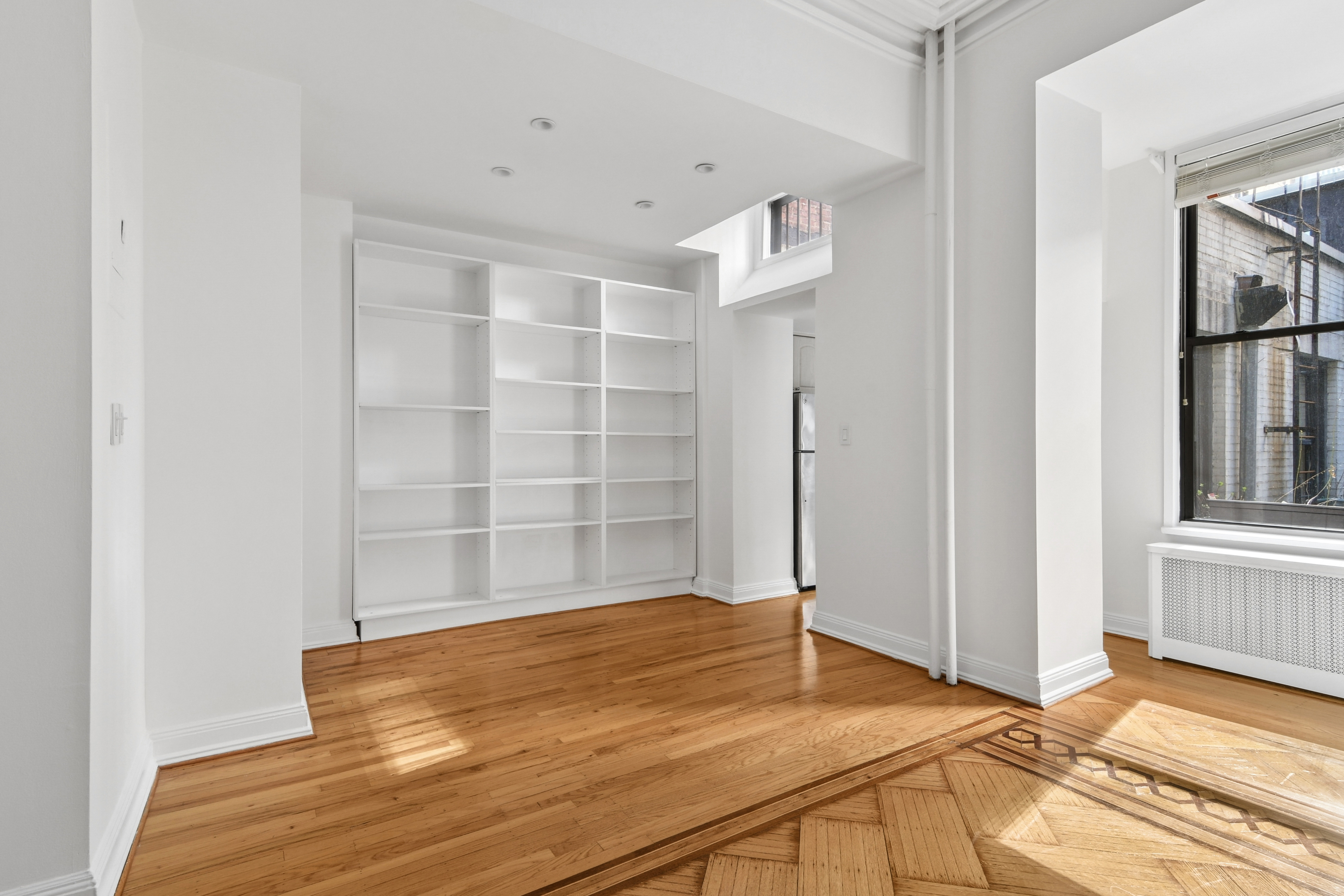109 East 38th Street, Unit 3A Manhattan, NY 10016 - Photo 3 of 13 a view of an empty room with wooden floor and a window