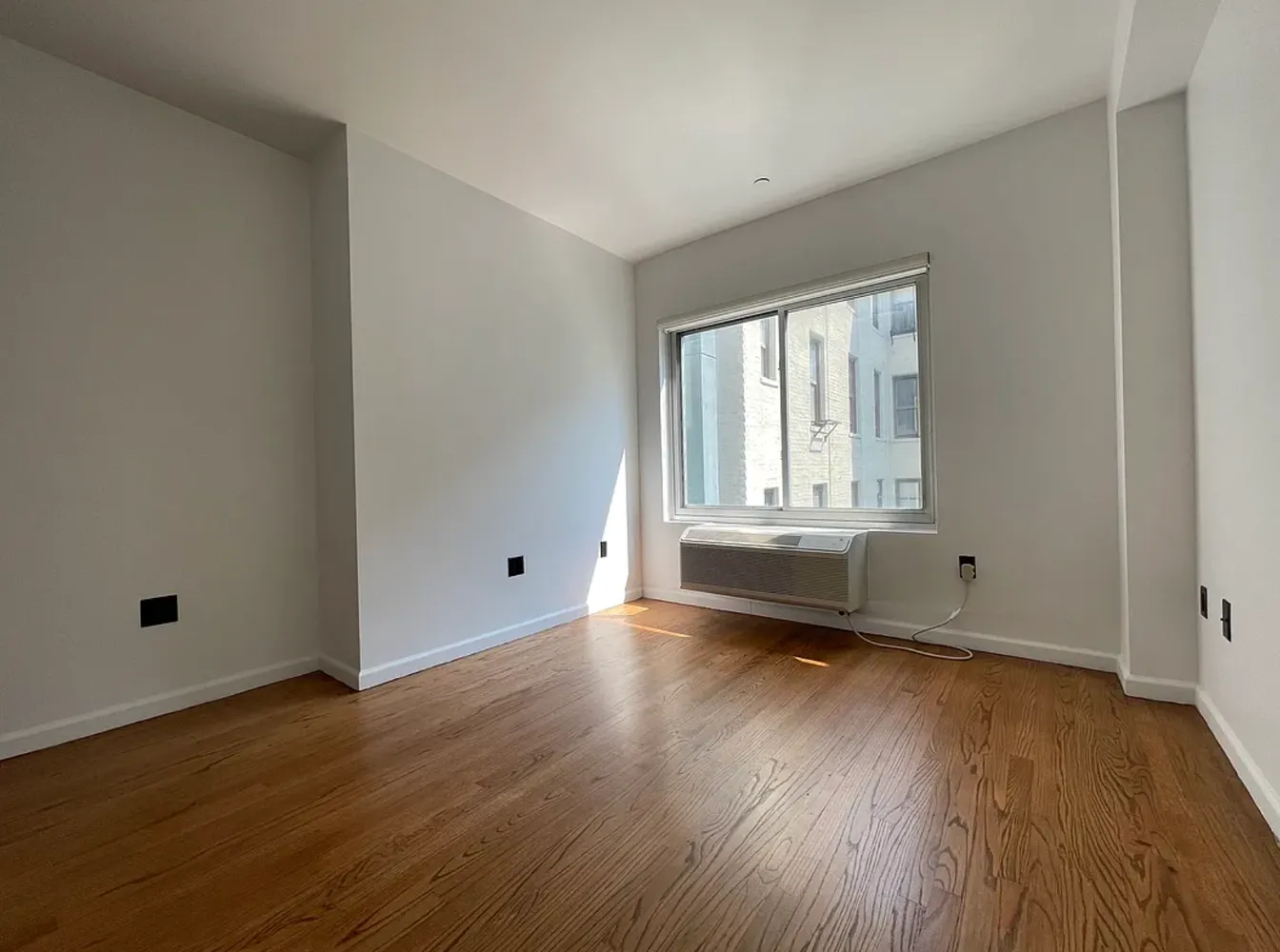 a view of a room with wooden floor and white walls