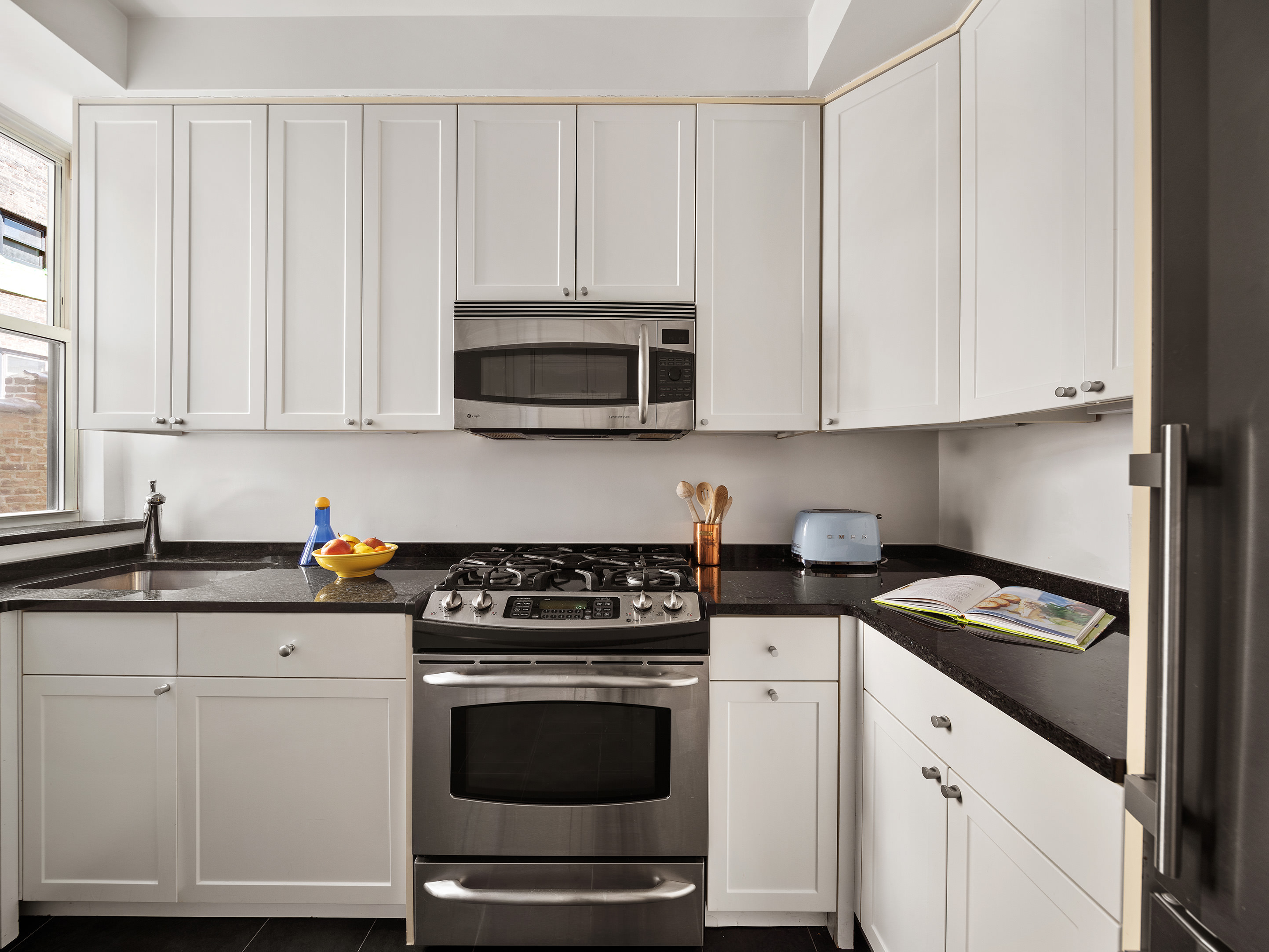 25 5th Avenue, Unit 8F Manhattan, NY 10003 - Photo 4 of 9 a kitchen with granite countertop white cabinets and stainless steel appliances