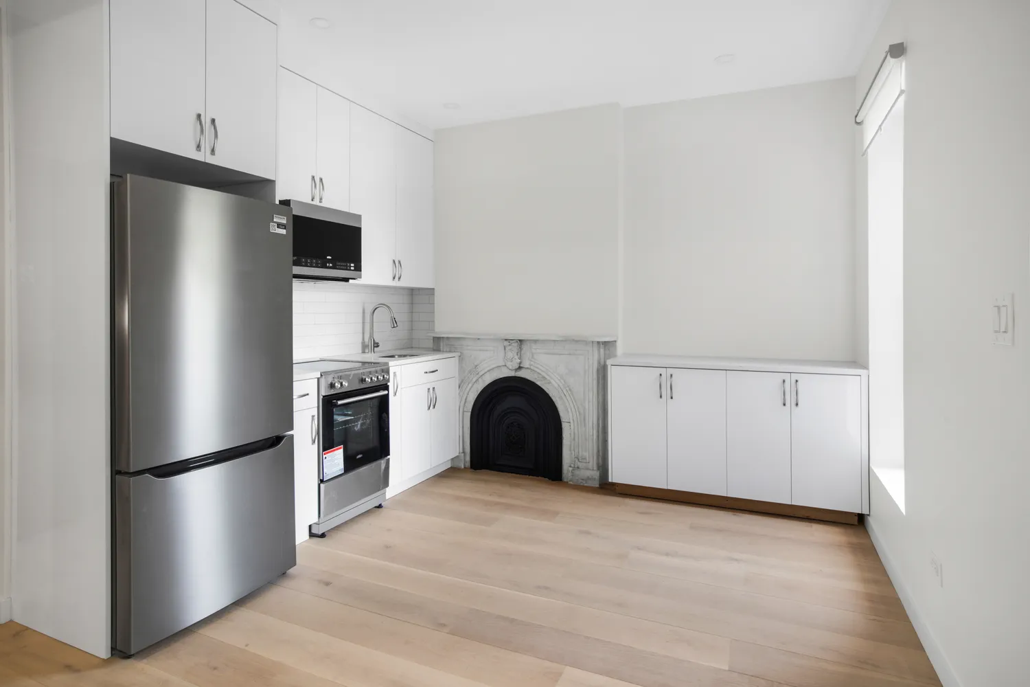 a view of kitchen with stainless steel appliances wooden floor and a window