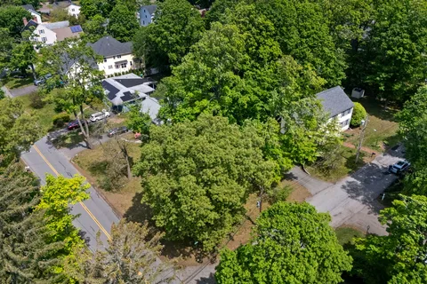 an aerial view of residential house with outdoor space and trees all around