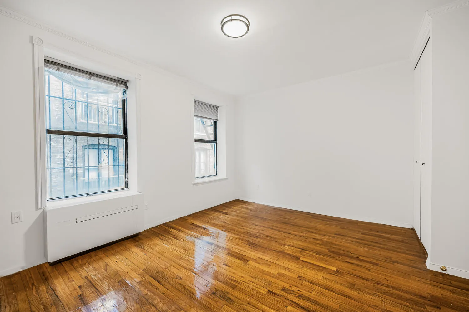 an empty room with wooden floor and windows