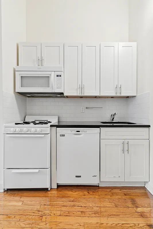1102 Dean Street, Unit 4 Brooklyn, NY 11216 - Photo 9 of 12 a kitchen with white cabinets and a stove