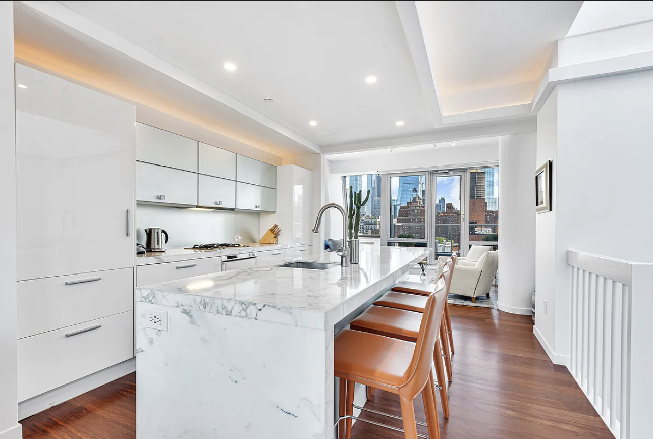 a open kitchen with white cabinets and wooden floor
