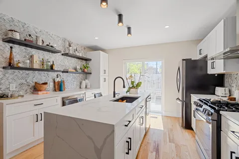 a kitchen with stainless steel appliances a sink a stove a refrigerator cabinets and a window