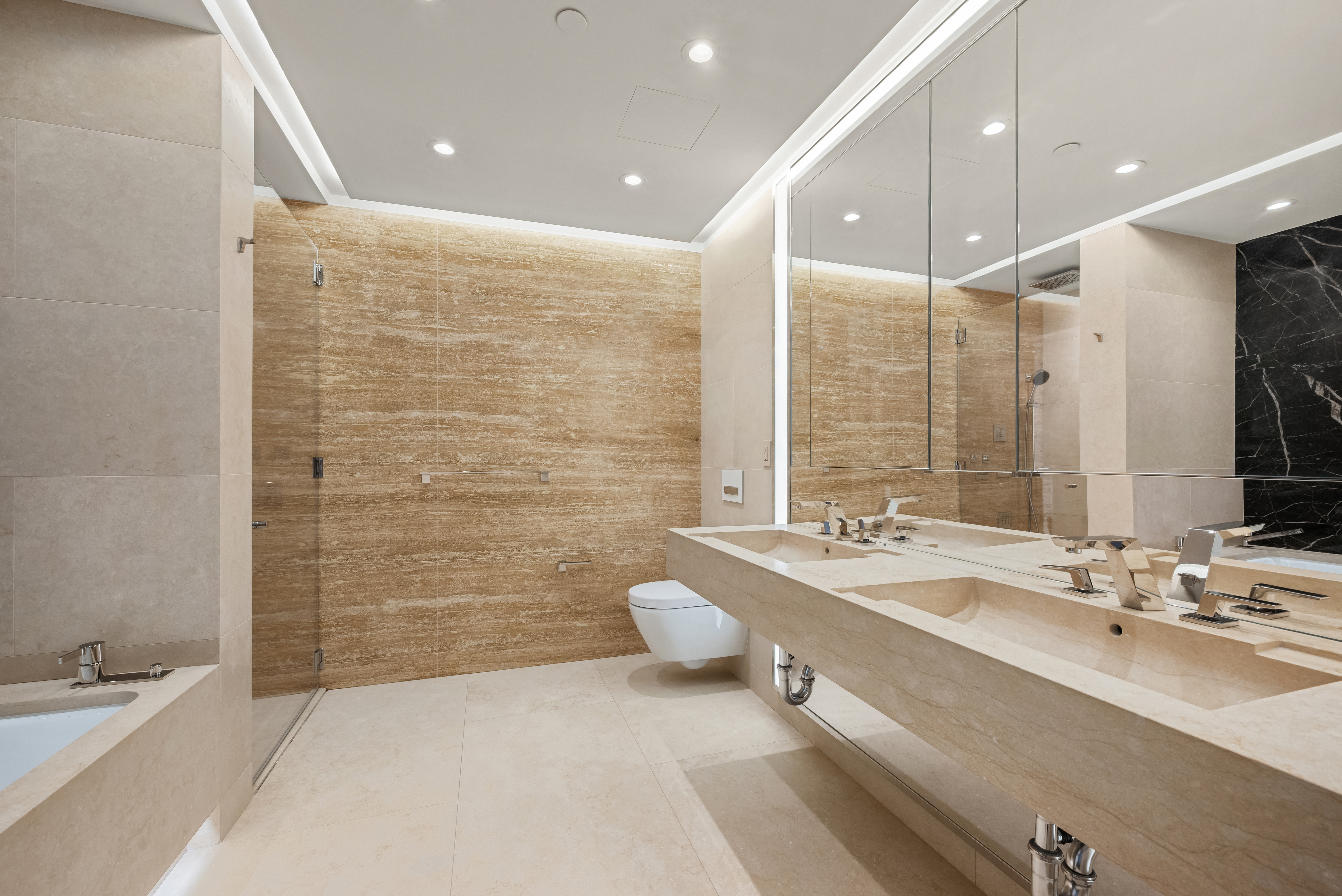 53 West 53rd Street, Unit 16C Manhattan, NY 10019 - Photo 9 of 12 a bathroom with a double vanity sink a mirror and a bathtub