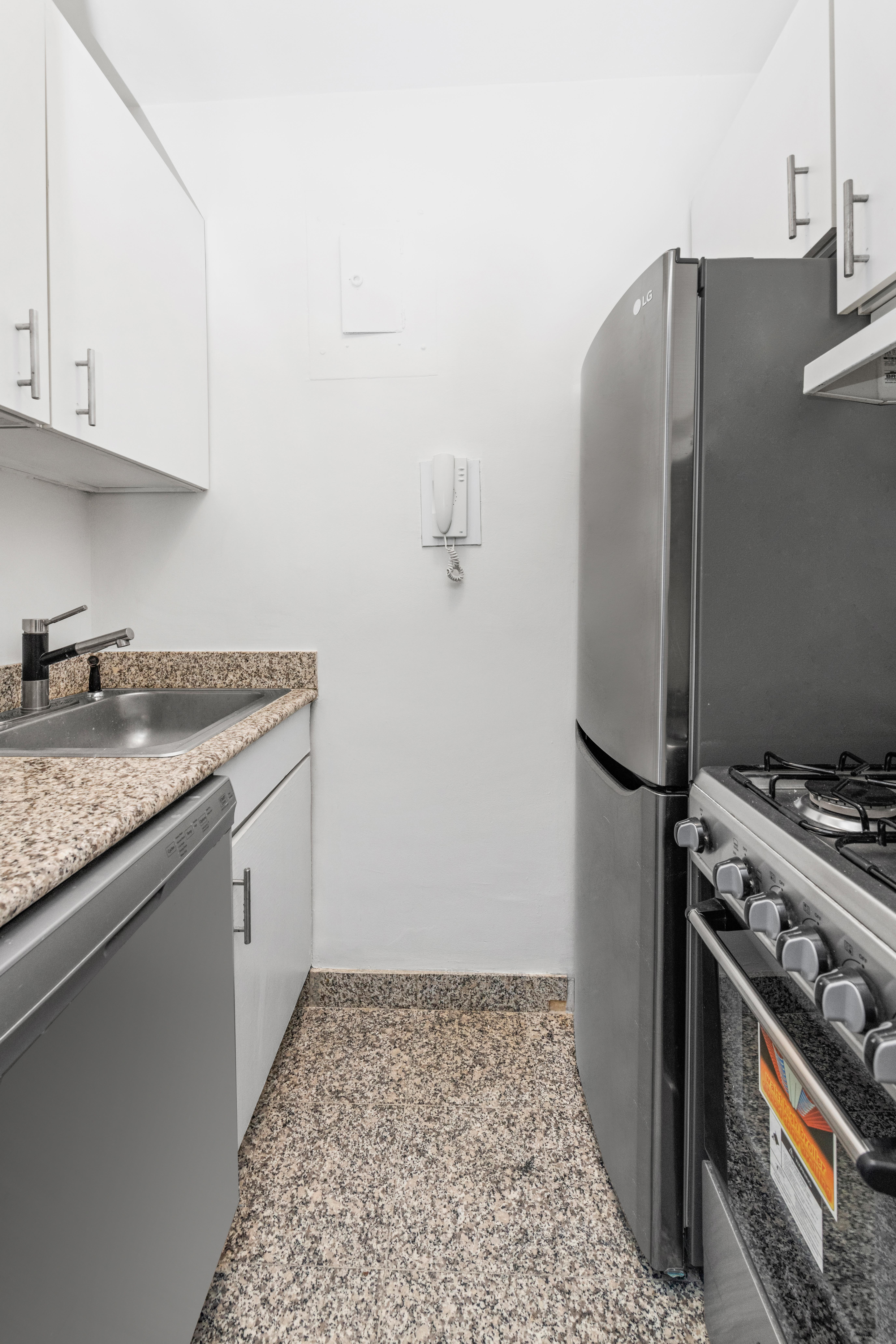 166 East 63rd Street, Unit 10L Manhattan, NY 10065 - Photo 3 of 7 a kitchen with stainless steel appliances granite countertop a refrigerator and a stove