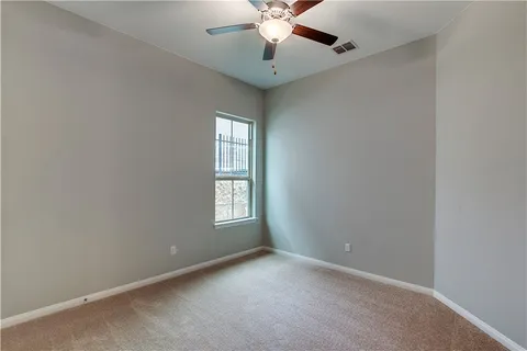 an empty room with windows and chandelier fan
