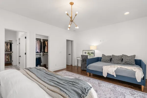 a bedroom with a bed ceiling fan and a wooden floor