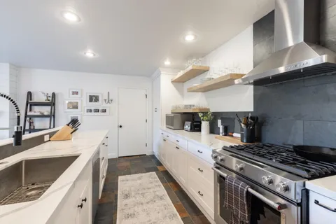 a large kitchen with stainless steel appliances granite countertop a stove and a sink